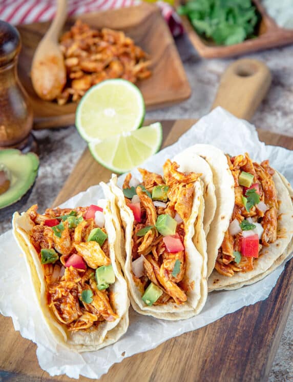 crockpot chicken tacos with shredded chicken and limes in the background